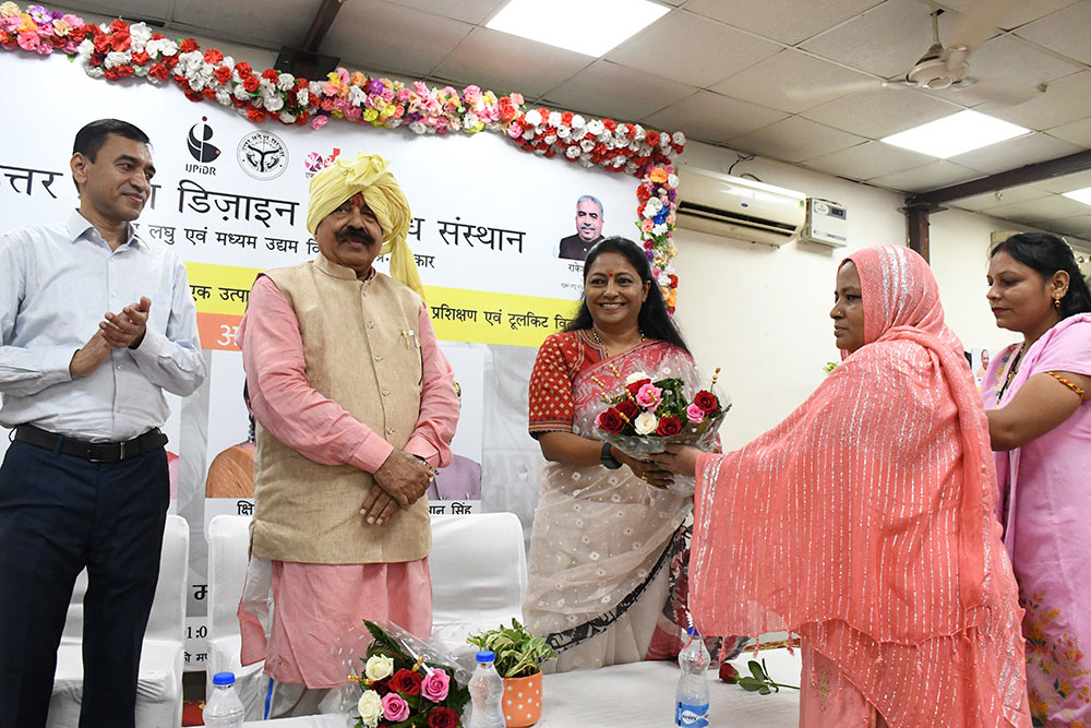 Two women are giving a flower buffet to the honorable Kshirpa Shukla on the stage of ODOP Agra.